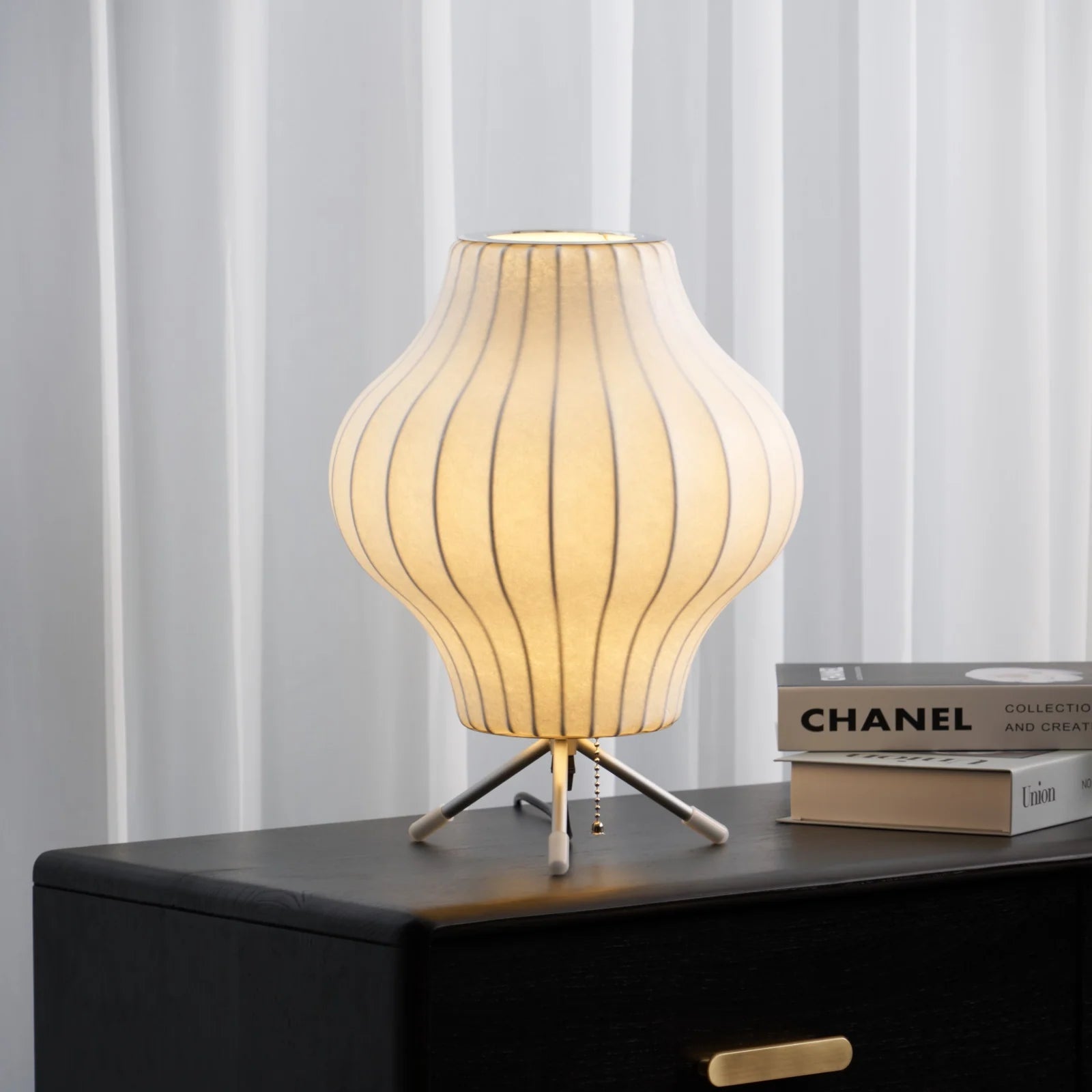 Table lamp with ribbed design on a dark surface with books in the background