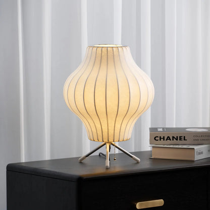 Table lamp with ribbed design on a dark surface with books in the background